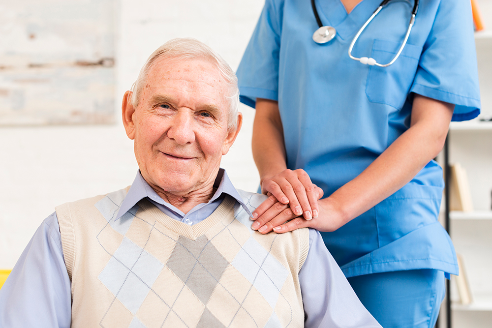 An Elderly Man Smiling With a Health Assistant